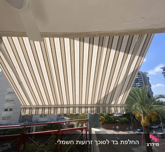סוכך בד פסים על מרפסת עם מעקה אדום